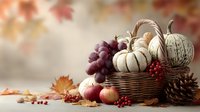 Autumn harvest still life with white pumpkins, grapes, apples, and pine cones in wicker basket against soft fall foliage background.