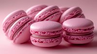 Pink French macarons with delicate almond meringue cookies filled with buttercream, arranged in soft lighting creating romantic mood for food photography.