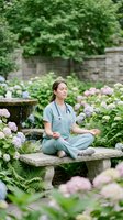 Young female healthcare worker in scrubs meditating peacefully in lush garden with hydrangea flowers, promoting wellness and mental health for medical professionals.