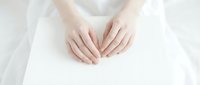 Delicate female hands resting gently on a white surface, soft natural light, clean minimalist composition for beauty, wellness, and skincare concepts.