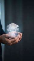Male hand holding glowing layered transparent squares with light effect against dark background, representing data storage, cloud computing, technology innovation, and digital solutions.