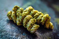 Fresh raw cannabis buds with trichomes on dark slate surface for medical marijuana dispensary products and natural herb photography.
