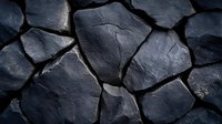 Dark stone wall with irregular shaped blocks creating natural pattern and texture. Rough surface of volcanic rocks fitted together in traditional masonry style.