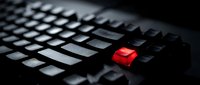 Black computer keyboard with single red key highlighted in dramatic lighting for technology and cybersecurity concepts in business presentations.