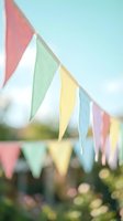 Colorful triangular bunting flags hanging outdoors against soft blue sky creating festive party atmosphere for celebrations and events.