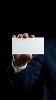Businessman in navy suit holding blank white card on dark background, mockup for branding, corporate identity or business card design.