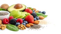 Fresh organic superfoods collection with avocado berries nuts seeds and leafy greens on white background for healthy nutrition and wellness lifestyle.