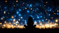 Silhouette of woman meditating against magical starry night sky with glowing blue and golden bokeh lights creating dreamy atmospheric background.