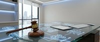 Modern law office with wooden gavel on glass desk displaying digital legal icons and documents in bright professional workspace with city view.