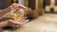 Hands protecting glowing sphere with network connections in warehouse logistics environment for business technology and supply chain management concepts.