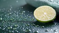 Fresh cut lime half with water drops on dark background, macro food photography showing citrus texture and juicy pulp detail. Refreshing culinary concept.