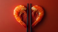Fresh cooked tiger shrimp arranged in heart shape with black chopsticks on red background, creative seafood concept for Valentine's day menu or romantic dinner.