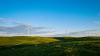 Wind turbines on rolling green hills under clear blue sky, renewable energy landscape for sustainable power generation and environmental conservation projects.