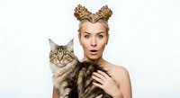 Woman with golden braided buns holding tabby cat, surprised expression, isolated on white background for portrait and pet-related design projects.