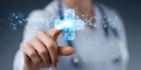 Medical professional in white coat pointing at glowing blue digital hologram cross with network connections, representing healthcare technology advancement.