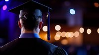 Graduate in cap and gown viewed from behind against colorful bokeh lights background celebrating academic achievement and educational milestone success.