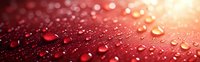 Water drops on red metallic surface with bokeh light effects creating luxurious abstract background with reflective dewdrops and glowing highlights.