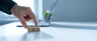 Business professional hand arranging wooden blocks with year 2024 numbers on modern office desk for planning and goal setting concepts.