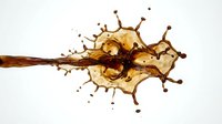 Coffee splash with dynamic droplets and crown formation on white background for beverage advertising and culinary design projects.