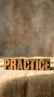 Wooden letterpress blocks spelling PRACTICE on burlap fabric with rustic background for motivation and skill development concepts.
