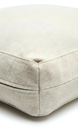 Close-up of a beige canvas tote bag bottom corner showing precise stitching and durable fabric texture on a light background.