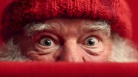 Surprised Santa Claus face with wide eyes peeking over red surface wearing knitted hat for Christmas holiday marketing and seasonal advertising campaigns.