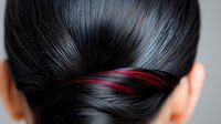 Close up view of sleek black hair with vibrant red highlights styled in an elegant twisted updo, showcasing professional hair coloring and styling technique.