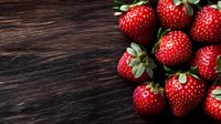 Fresh ripe strawberries with green leaves arranged on dark wooden rustic background. Natural organic berries with copy space for text.