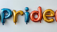 Colorful foil balloon letters spelling pride in rainbow colors against white background, celebration and equality concept for pride month events and festivals.