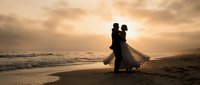 Romantic couple silhouette dancing on beach at sunset with golden sky and ocean waves creating dreamy wedding or engagement scene for love concepts.
