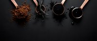 Four copper spoons filled with different chocolate ingredients including cocoa powder and melted chocolate on dark background for baking and confectionery.