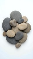 Collection of smooth river stones and pebbles in natural earth tones isolated on white background for spa wellness meditation and zen design projects.