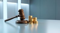 Wooden judge gavel next to stack of golden coins on white desk in modern office interior representing legal fees, financial litigation and court costs.