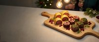 Festive holiday cheese and charcuterie board with crackers, grapes and nuts on wooden serving platter. Christmas appetizer spread for entertaining guests.