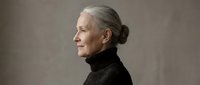 Senior Caucasian woman with gray hair in elegant black turtleneck sweater, profile portrait against neutral background for lifestyle and aging concepts.