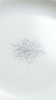 Pile of fine silver metallic threads scattered on white background creating abstract texture pattern for craft and textile design projects.