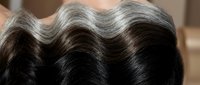 Close-up of lustrous dark brown hair with natural waves showing healthy shine and texture for beauty and haircare concepts.