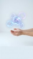 Hands catching colorful soap bubbles floating in air against white background for skincare and beauty product advertising campaigns.