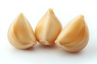 Fresh peeled garlic cloves arranged in row on white background, macro food photography showing texture and natural organic ingredients for cooking.
