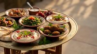 Traditional Middle Eastern mezze platter with hummus, falafel, tabbouleh and assorted appetizers served on ornate brass tray for authentic dining experience.