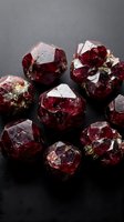 Raw red garnet gemstones with natural crystal formations on dark surface for jewelry making and mineral collection displays.