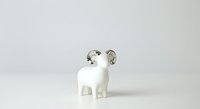 Ceramic white goat figurine with silver horns and accents, isolated on white background, suitable for home decor, collectibles, and design projects.