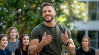 Charismatic male speaker gesturing expressively while presenting to diverse group of young people outdoors on campus, showing confidence and engagement in natural light.