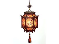 Ornate hexagonal hanging lantern with warm amber glass panels and decorative brass metalwork, featuring traditional Asian-inspired design with tassel detail for home decor and lighting.