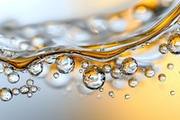 Macro photography of transparent water drops and golden liquid waves creating abstract pattern with light refraction and surface tension effects.