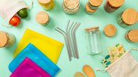 Eco-friendly zero waste lifestyle flat lay with reusable items, bamboo products, metal straws and colorful cleaning cloths on mint background.
