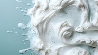 Creamy white milk or yogurt splash with dynamic swirls and droplets on light turquoise background, creating artistic fluid motion pattern for dairy product advertising.