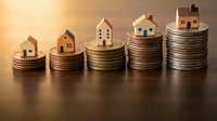 Wooden houses stacked on increasing coin piles representing property investment growth, wealth accumulation, and real estate financial planning concepts.