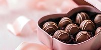 Luxury chocolate truffles in heart-shaped pink gift box against soft blurred background, romantic sweet dessert composition for Valentine's Day celebration.