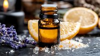 Small bottle of essential oil with fresh orange slices and lavender flowers on dark background, aromatic spa composition with himalayan salt crystals.